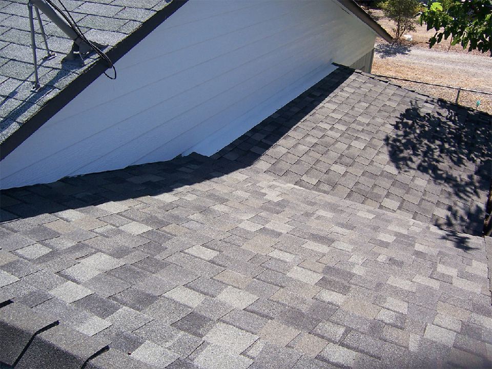 New composition shingles being laid over fresh underlayment on a Redding-area reroof