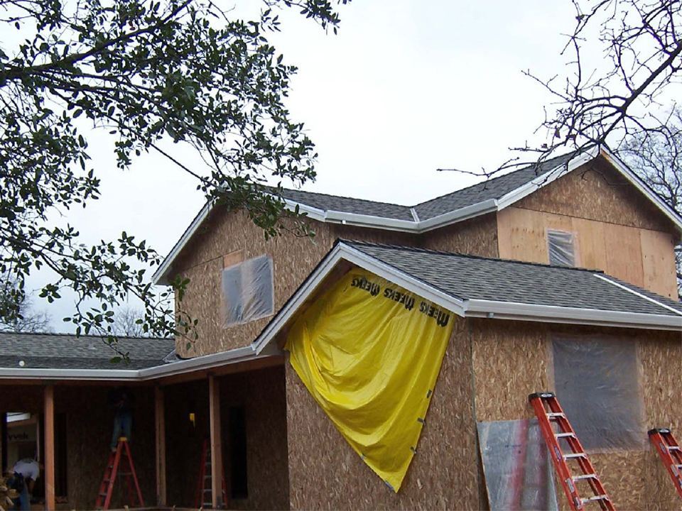 Home mid-project with new roofing installed and wall wrap still exposed