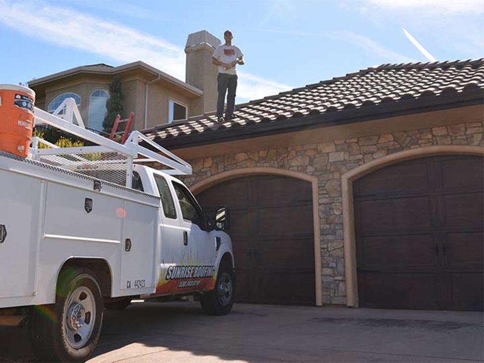 Completed tile roof with a Sunrise Roofing truck parked at the home