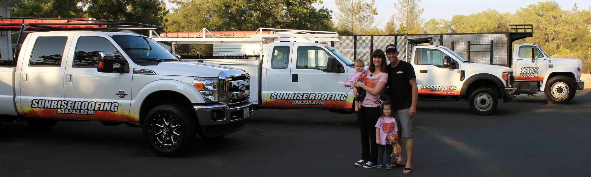 The Sunrise Roofing family standing in front of the company's branded service trucks in Redding, California