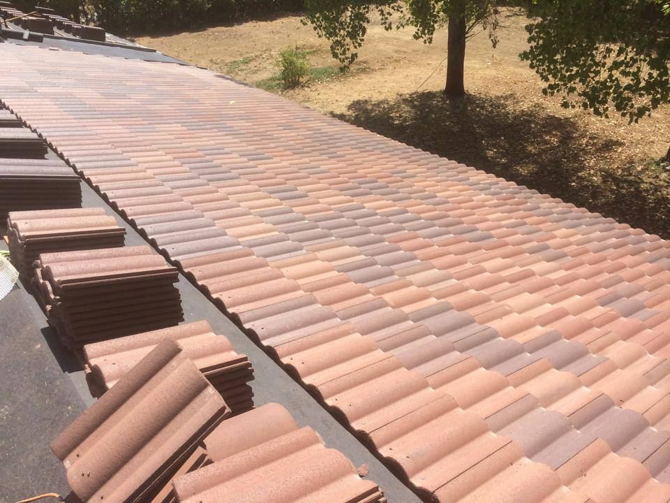 Clay tile roof partially installed, with remaining tile stacked along the deck
