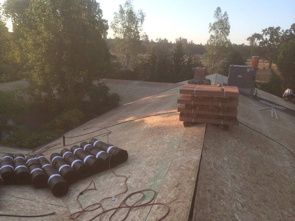 Roof vents and tile bundles staged on a prepared roof deck at sunrise