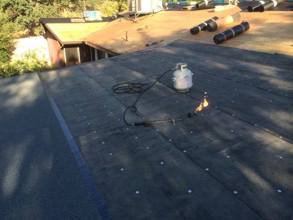 Torch-applied low-slope membrane roofing in progress on a flat roof section